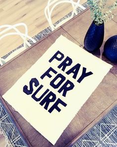 a sign that says pray for surf next to two vases with flowers