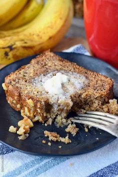 a piece of cake on a plate with a fork and some bananas in the background