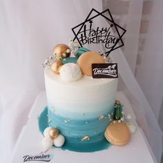 a birthday cake with frosting and decorations on the top is decorated in blue, white and gold