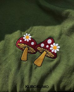 two mushrooms with flowers on them are embroidered onto a green shirt