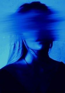 a blurry photo of a woman's face with blue light in the background