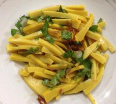 a white plate topped with pasta covered in cheese and cilantro sauce, garnished with parsley