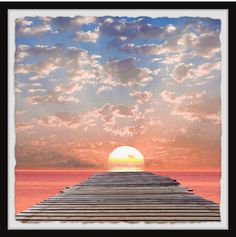 the sun is setting over an ocean with a pier in the foreground and clouds in the background