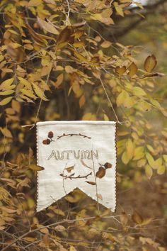 an autumn banner hanging from a tree branch