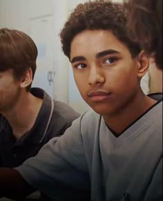 two young men sitting next to each other in front of a bathroom mirror looking at the camera