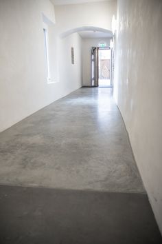 an empty hallway with white walls and concrete flooring is seen in this image from the bottom