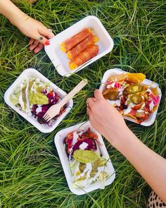 people are sitting in the grass eating food from plastic containers with forks and spoons