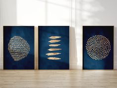 three blue and gold art pieces on a wooden floor