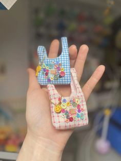 a hand holding two small purses with buttons on them