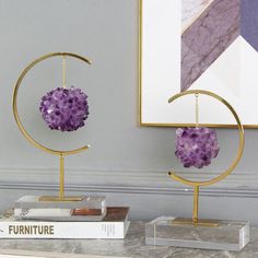 two purple flowers are hanging from gold hoop holders