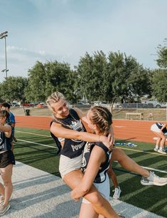 the girls are hugging each other on the field