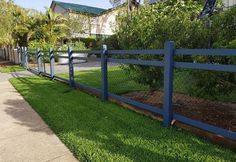 a blue fence is in front of a house and some grass on the side walk