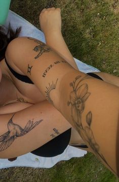 a woman laying on the ground with tattoos on her legs and leggings,