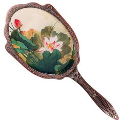 a mirror with flowers painted on it is hanging from the handle and has an ornate frame