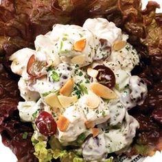 a salad with grapes, almonds and dressing on it