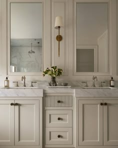 a bathroom with two sinks and mirrors on the wall next to each other in white cabinets