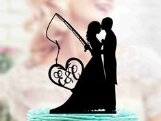 a wedding cake topper with a bride and groom holding a fishing rod in the shape of a heart