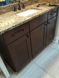 a bathroom vanity with marble counter top and brown cabinets