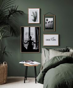 a bedroom with green walls and pictures hanging on the wall above the bed, along with a small side table