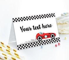 a card with a red race car on it next to some cupcakes and candy