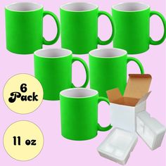 six green coffee mugs are next to a cardboard box and some pieces of paper