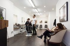 two men and a woman are sitting in a hairdressers's salon