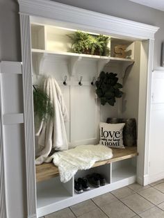 a white coat rack filled with coats and shoes on top of a wooden shelf next to a door