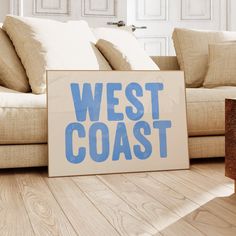 a sign that says west coast on it in front of a couch and coffee table