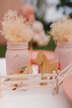 two pink mason jars filled with baby's breath flowers sitting on top of a table