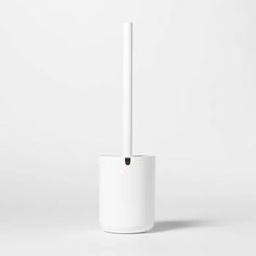 a white toilet brush sitting on top of a white cup