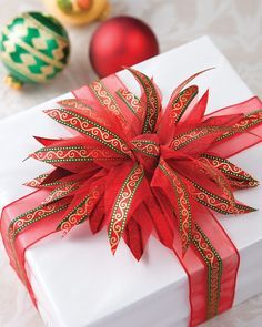 a white gift box with red ribbon and ornaments around it