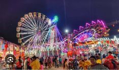 an amusement park at night with people walking around and ferris wheel in the foreground