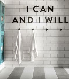 two white towels hanging on the wall next to each other in front of a black and white checkered floor