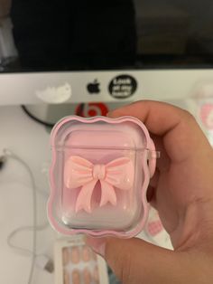 a hand holding an apple airpods case with a pink bow on the front and side