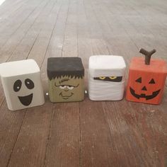 four different colored blocks with faces on them sitting on a wooden floor next to each other