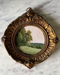 a painting is shown in an ornate frame on a marble countertop with a tree