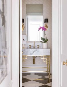 a bathroom with a checkered floor and marble counter top, gold fixtures and a mirror