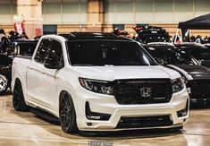 the front end of a white truck parked in a parking lot next to other cars