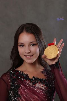 a woman holding up a gold medal in front of her face