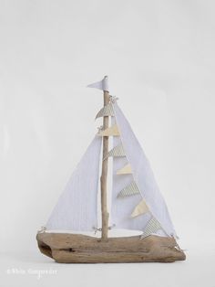 a small wooden sailboat with white sails on a driftwood base, in the shape of a christmas tree