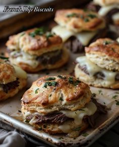 several mini sandwiches with cheese and meat on a baking sheet, ready to be eaten