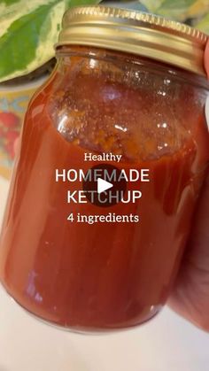 a hand holding a jar of homemade ketchup