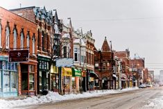 a snowy street lined with buildings and shops