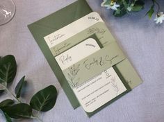 the wedding stationery is laid out on top of the table with flowers and greenery