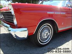 an old red car with chrome rims parked on the street