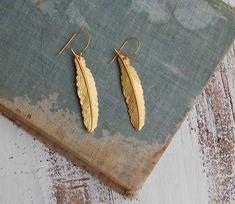 Delicate gold feather earrings. These bohemian inspired brass feather earrings dangle from simple gold plate ear wires. A lovely addition for your Autumn or winter wardrobe. Each earring measures approx. 2 1/4 inches from the top of the ear-wire to the bottom of the feather charm. PLEASE NOTE: ►There are NO returns on earrings (for health/hygiene reasons) Your earrings will arrive in a beige cotton drawstring gift bag with a gift tag. Perfect for gift giving or a fun little treat for yourself. T Gold Feather Earrings As A Gift, Gold Feather Earrings For Gift, Gold Feather Earrings, Drawstring Gift Bag, Health Hygiene, Gold Feathers, Nature Birds, Feather Charms, Feather Earrings