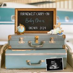 two suitcases stacked on top of each other in front of a sign that says, our newest carry - on baby twins due