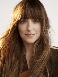 a woman with long hair is posing for a magazine cover shot, wearing a brown coat