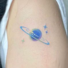 a small tattoo on the back of a woman's shoulder with an image of saturn and stars