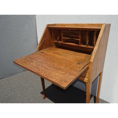 an old wooden desk with drawers on the top and bottom, sitting in front of a wall